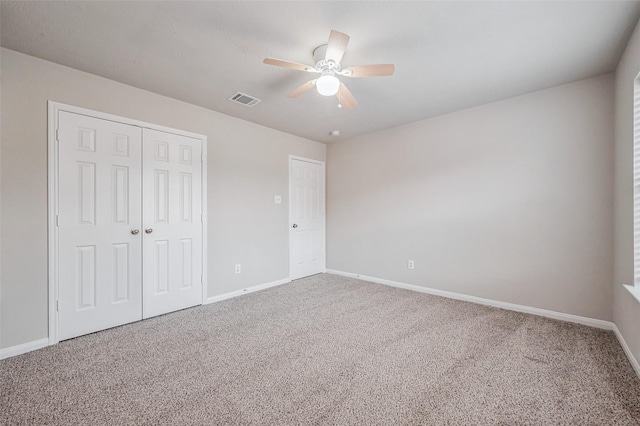 unfurnished bedroom featuring visible vents, baseboards, carpet flooring, a closet, and a ceiling fan