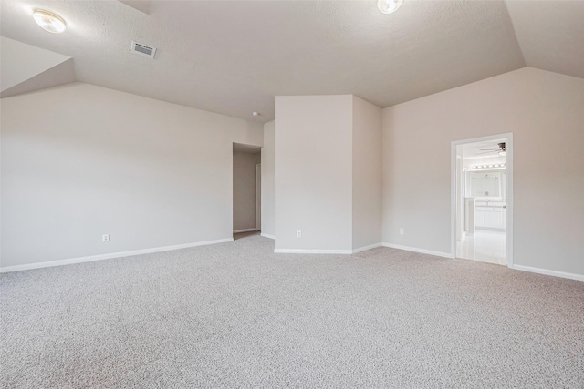 spare room featuring visible vents, carpet floors, baseboards, and vaulted ceiling