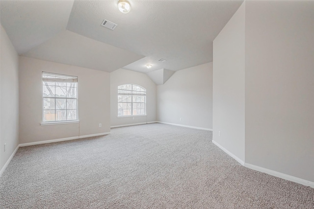 carpeted spare room with visible vents, baseboards, and vaulted ceiling