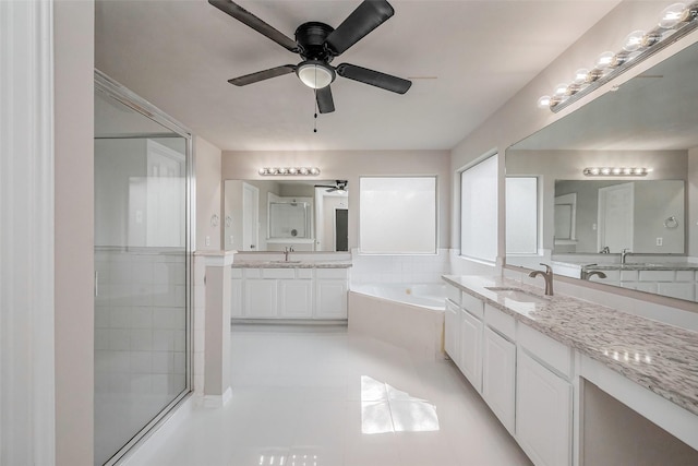 bathroom featuring a bath, tile patterned flooring, two vanities, and a sink