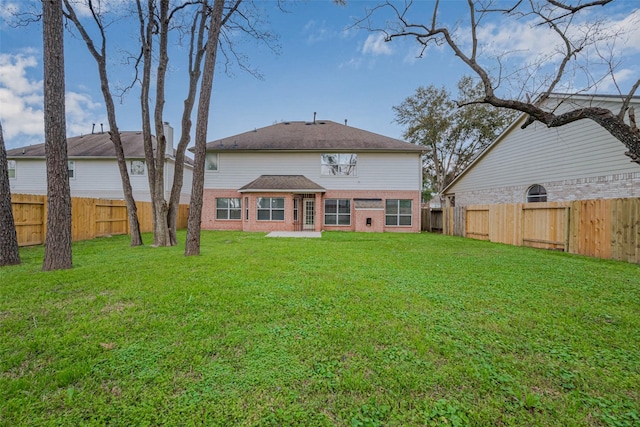 back of property featuring a lawn, a fenced backyard, and brick siding