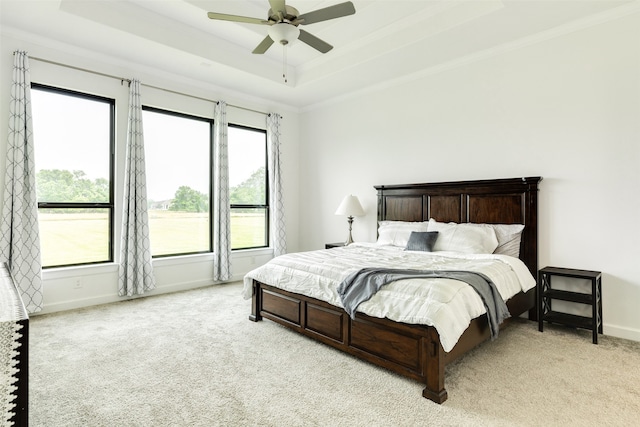 bedroom with baseboards, a raised ceiling, light carpet, and a ceiling fan