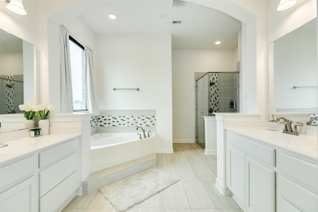 bathroom featuring two vanities, a stall shower, a sink, recessed lighting, and a bath