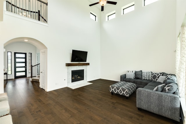 living area featuring baseboards, arched walkways, ceiling fan, and dark wood-style flooring