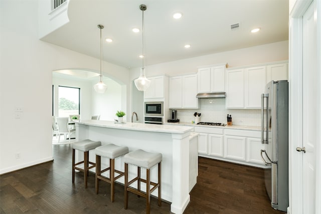 kitchen featuring visible vents, backsplash, stainless steel appliances, arched walkways, and light countertops