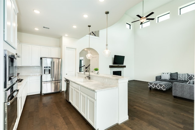 kitchen with open floor plan, appliances with stainless steel finishes, a fireplace, and a sink