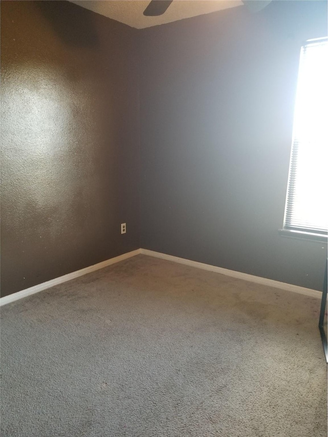 empty room featuring baseboards, carpet floors, and a ceiling fan