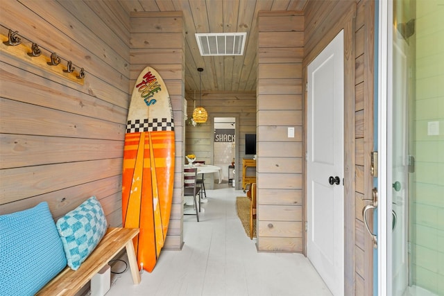 hall with wooden walls, wood ceiling, and visible vents