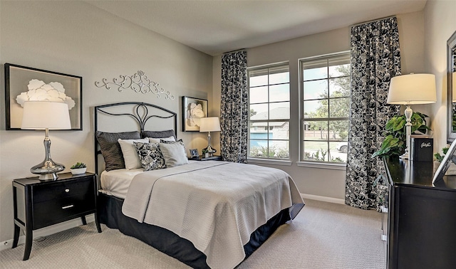 bedroom with light colored carpet, baseboards, and multiple windows