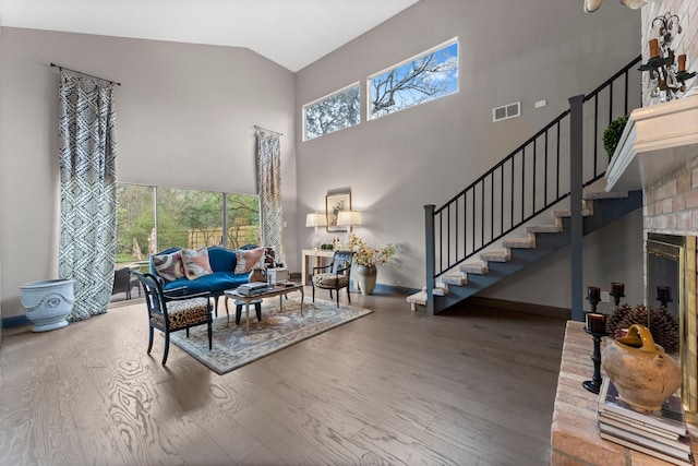 living area featuring stairway, high vaulted ceiling, visible vents, and wood finished floors