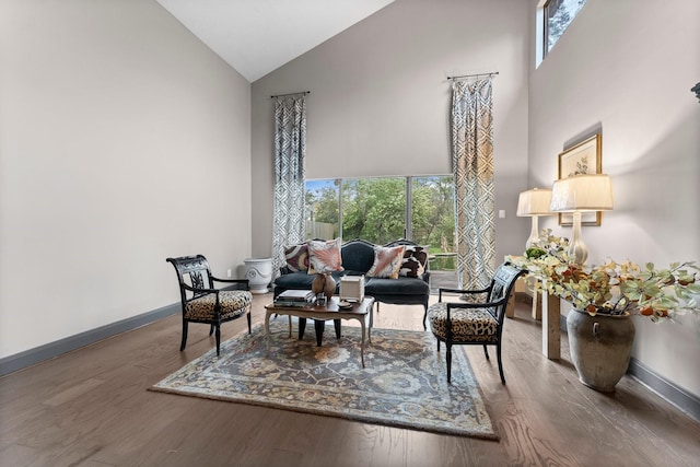 sitting room with wood finished floors, baseboards, and high vaulted ceiling