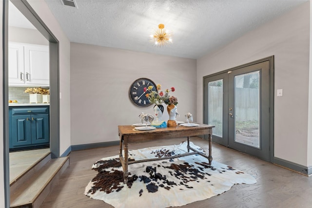 home office featuring visible vents, light wood-style flooring, a textured ceiling, french doors, and baseboards