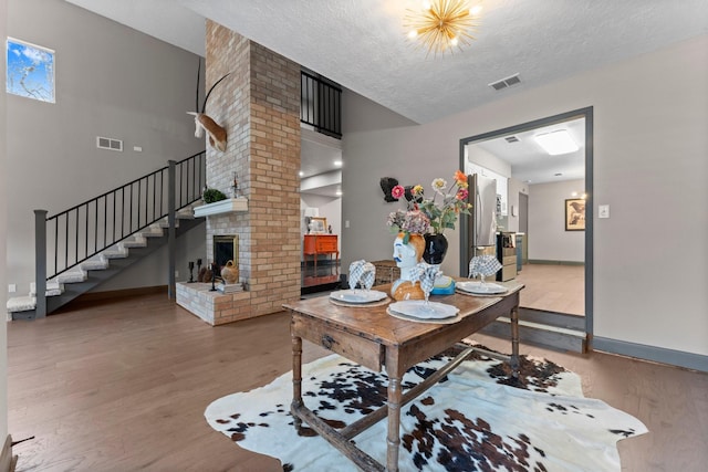 dining area with visible vents, a fireplace, stairs, and light wood-style floors