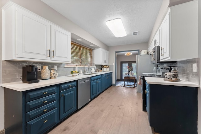 kitchen with visible vents, light wood-style flooring, blue cabinetry, a sink, and appliances with stainless steel finishes