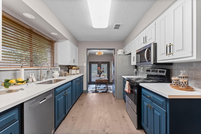 kitchen featuring visible vents, blue cabinetry, a sink, stainless steel appliances, and light wood-style floors