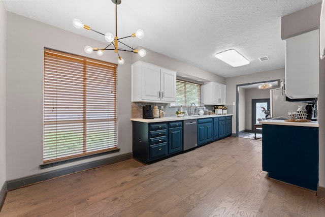 kitchen featuring blue cabinetry, light wood-style flooring, a notable chandelier, white cabinets, and stainless steel dishwasher