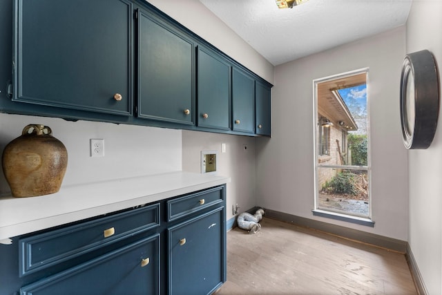 laundry area featuring light wood-style floors, hookup for a washing machine, cabinet space, and baseboards