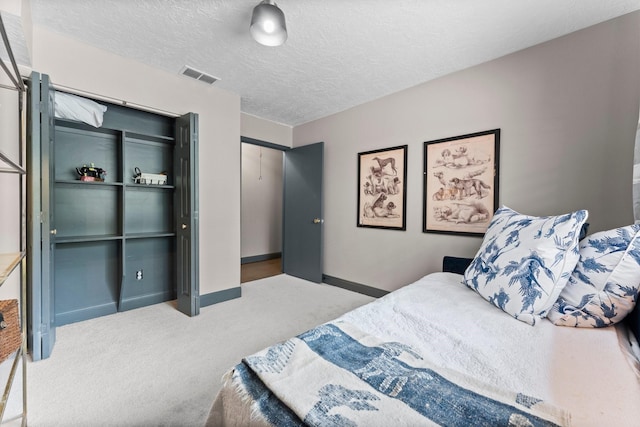 bedroom featuring carpet flooring, baseboards, visible vents, and a textured ceiling