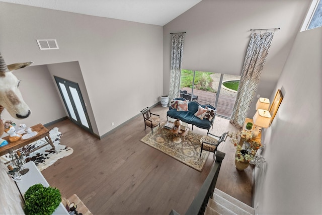 living area with plenty of natural light, wood finished floors, visible vents, and high vaulted ceiling