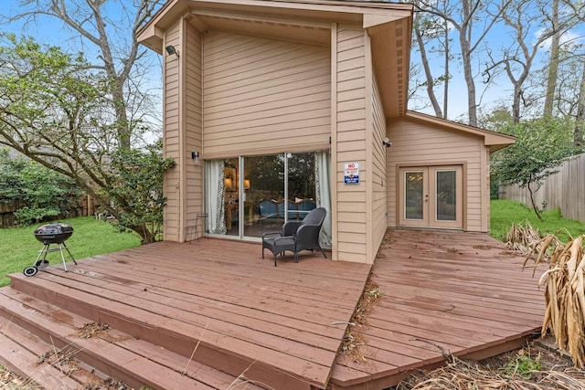 wooden terrace with a lawn, french doors, and a fenced backyard