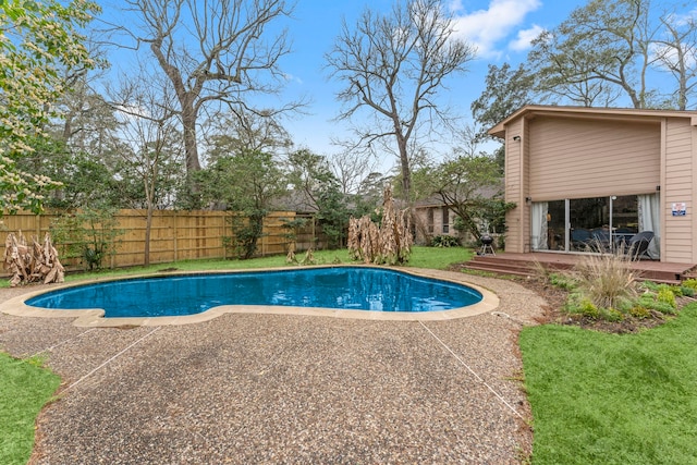 view of swimming pool featuring a fenced in pool, fence, a wooden deck, a yard, and a patio area