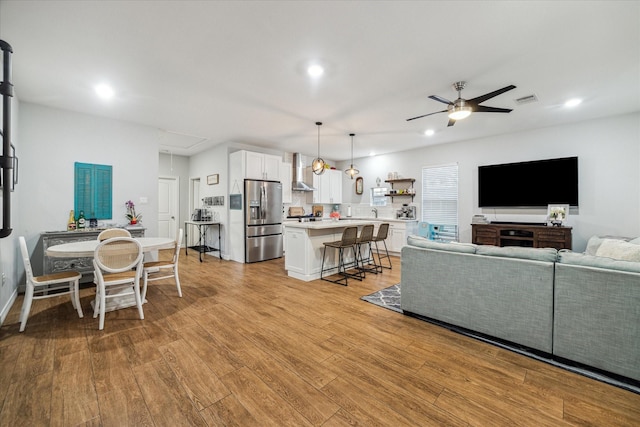 living room featuring a ceiling fan, visible vents, attic access, recessed lighting, and light wood-style floors