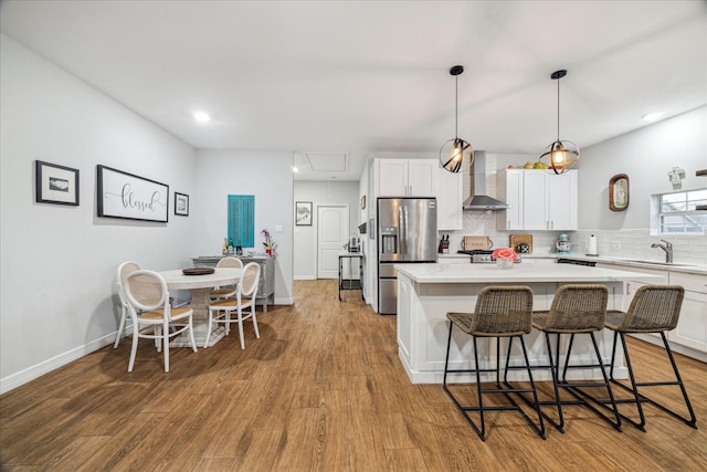 4113 Ella Blvd, Houston, TX 77018 - kitchen featuring a center island, stainless steel fridge with ice dispenser, a breakfast bar, light countertops, and wall chimney exhaust hood