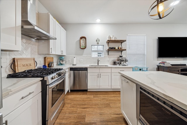 4113 Ella Blvd, Houston, TX 77018 - kitchen with white cabinetry, wall chimney range hood, light wood finished floors, and appliances with stainless steel finishes