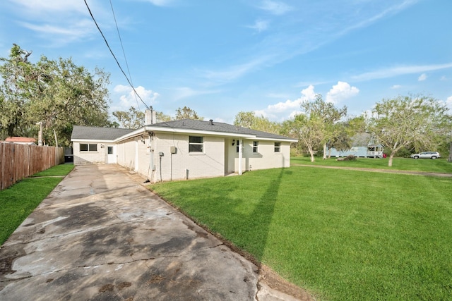 view of front of house featuring fence, a chimney, a front lawn, concrete driveway, and brick siding