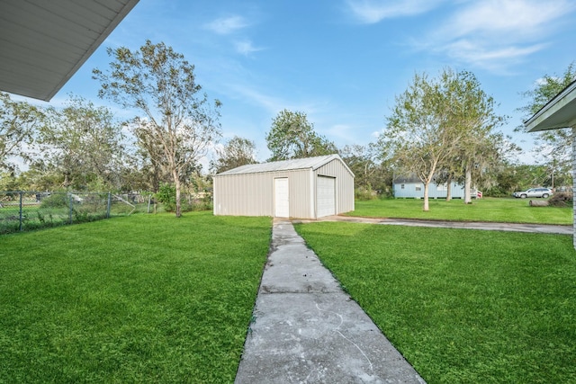 view of yard featuring driveway, a detached garage, an outdoor structure, and fence