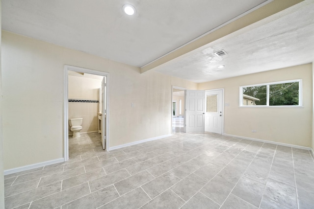 unfurnished bedroom with light tile patterned floors, baseboards, visible vents, and connected bathroom