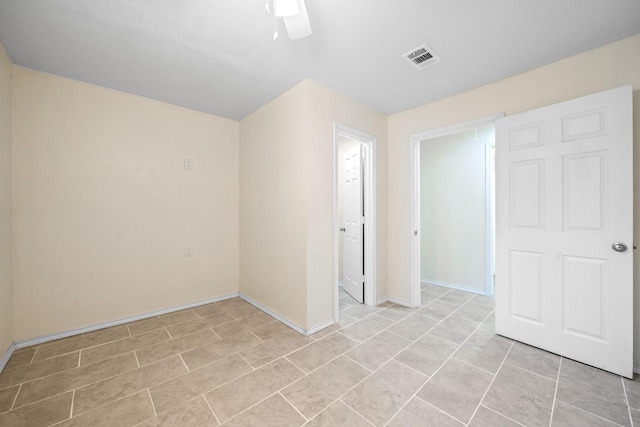 unfurnished room with light tile patterned floors, visible vents, a ceiling fan, and baseboards