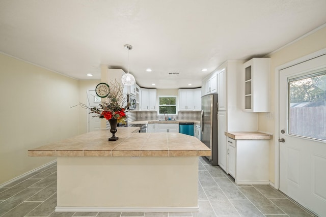 kitchen with visible vents, a peninsula, stainless steel appliances, white cabinetry, and tasteful backsplash