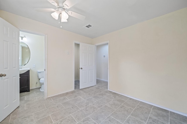 unfurnished bedroom featuring a ceiling fan, visible vents, ensuite bathroom, and baseboards