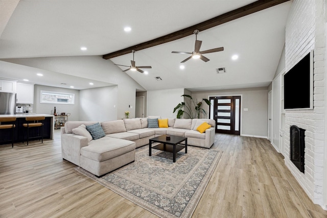 living room featuring beam ceiling, a brick fireplace, visible vents, and light wood-type flooring