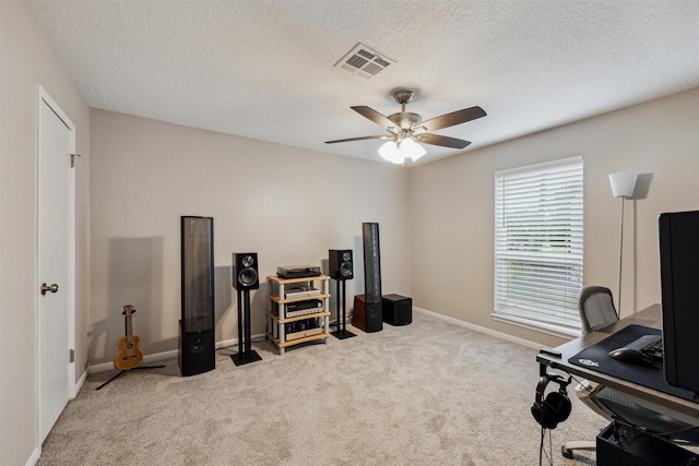 carpeted office space with visible vents, baseboards, a textured ceiling, and a ceiling fan