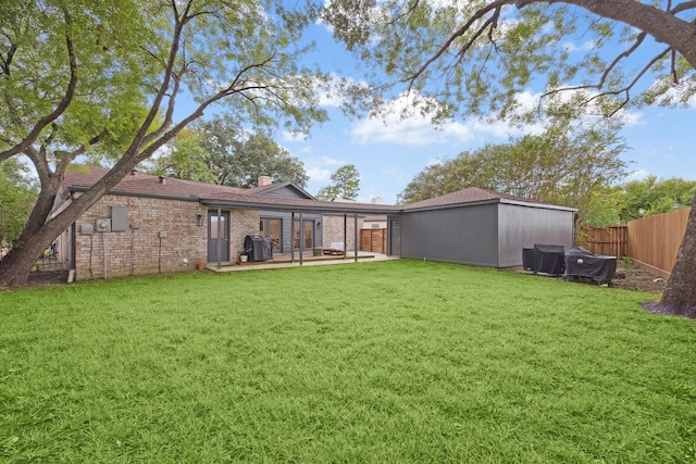 back of house with a yard, brick siding, a chimney, and fence