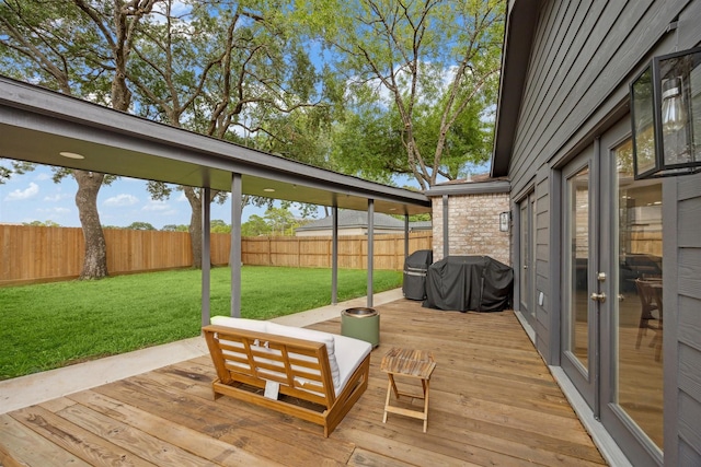 wooden deck featuring grilling area, a lawn, and fence