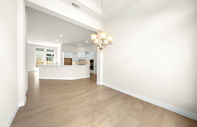 unfurnished living room with visible vents, recessed lighting, light wood-style floors, an inviting chandelier, and baseboards