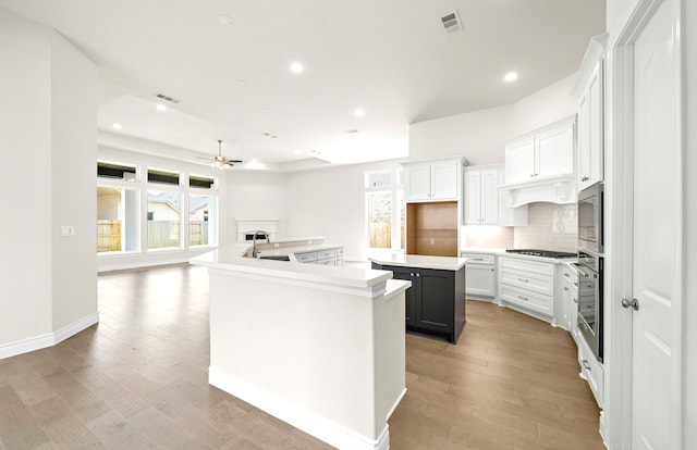 kitchen with visible vents, a large island, stainless steel appliances, light wood-style floors, and decorative backsplash