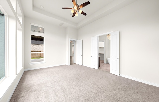 unfurnished bedroom with visible vents, baseboards, carpet, a towering ceiling, and a raised ceiling