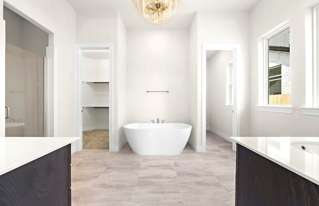 bathroom with a shower stall, baseboards, a chandelier, a soaking tub, and vanity