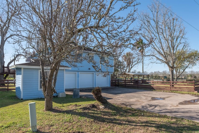 exterior space featuring fence, a lawn, a garage, and driveway