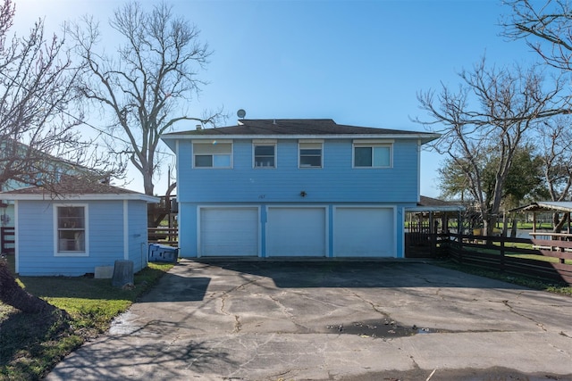 back of house with a garage, driveway, and fence