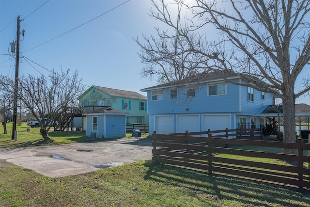 exterior space with driveway, an attached garage, a front yard, and fence