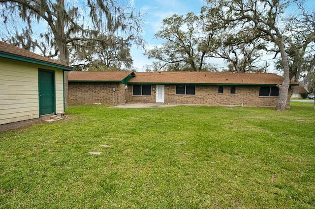 rear view of house with a patio, a lawn, and brick siding