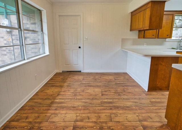 kitchen featuring brown cabinetry, a peninsula, light countertops, and dark wood-style flooring