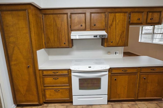 kitchen with light countertops, ventilation hood, brown cabinetry, and white electric stove