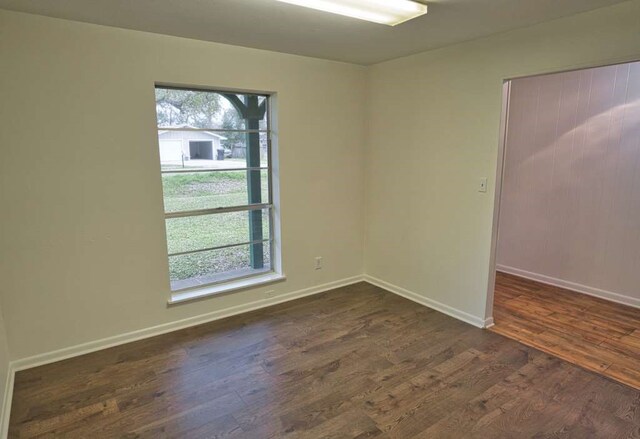 unfurnished room with a wealth of natural light, baseboards, and dark wood-style flooring