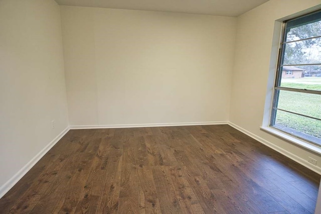 unfurnished room with dark wood finished floors and baseboards